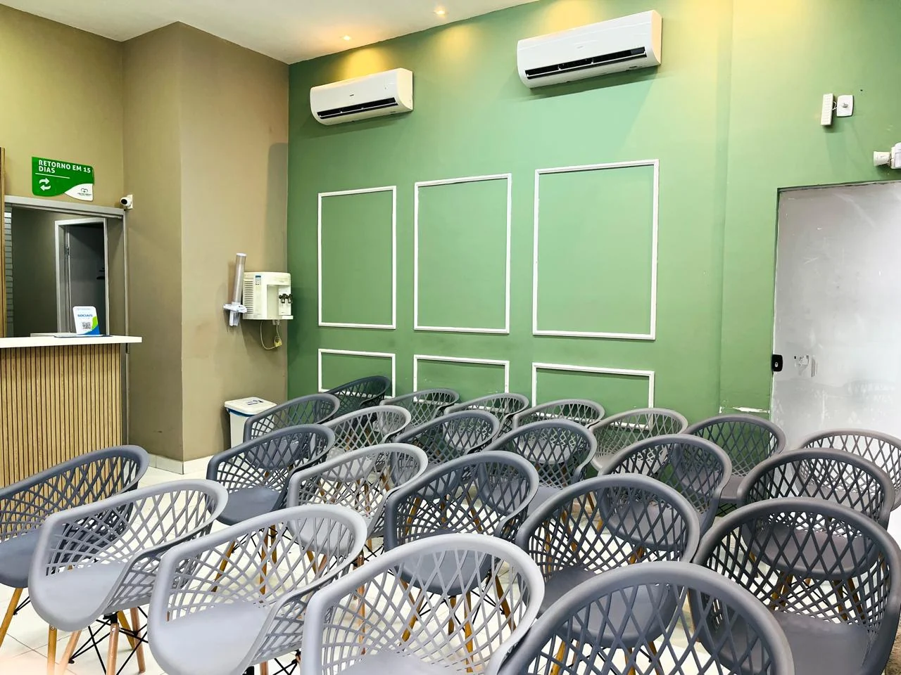 Sala de espera ampla com cadeiras e parede verde
